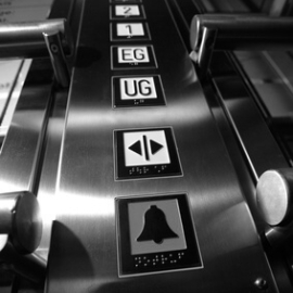 Foto von einer Fahrstuhlbedienung mit tastbaren Symbolen und Braille-Schrift